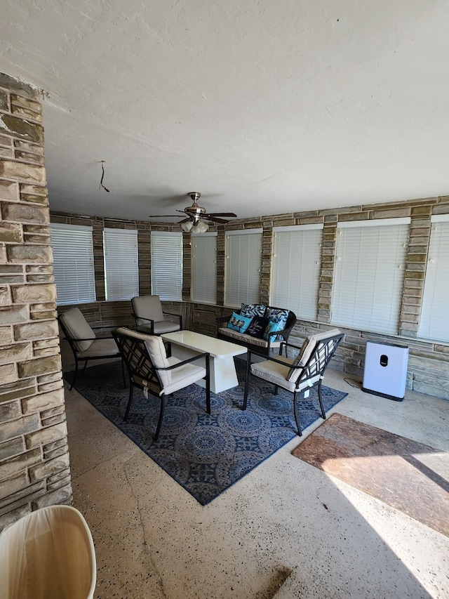 living area with a ceiling fan and speckled floor