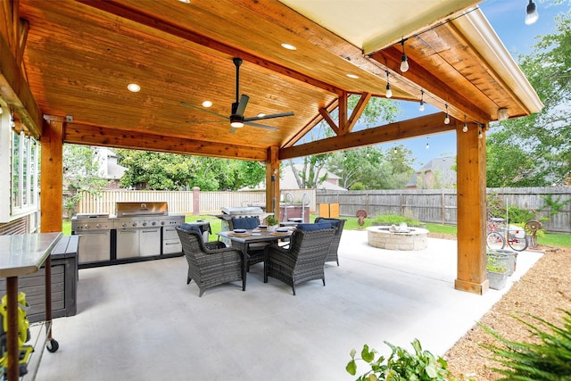 view of patio featuring an outdoor fire pit, exterior kitchen, a fenced backyard, area for grilling, and outdoor dining space