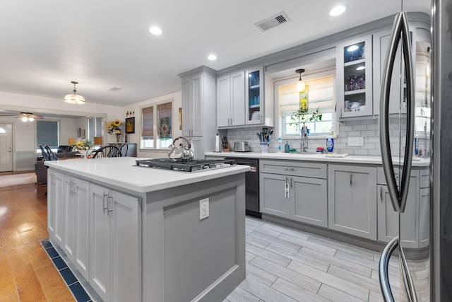 2120 73rd St, Galveston, TX 77551 - kitchen featuring appliances with stainless steel finishes, gray cabinetry, a center island, a sink, and tasteful backsplash