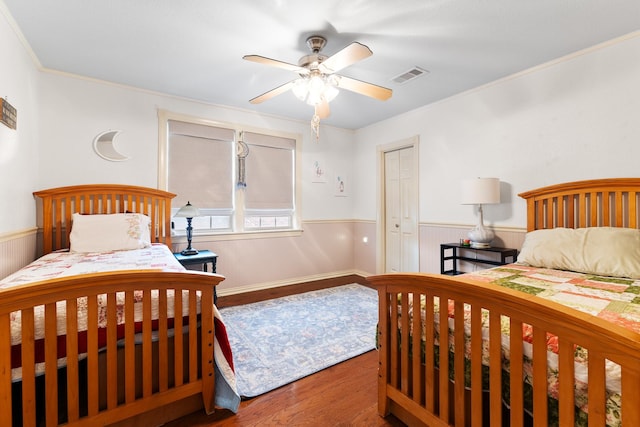 2120 73rd St, Galveston, TX 77551 - bedroom featuring a wainscoted wall, wood finished floors, ornamental molding, a ceiling fan, and a closet