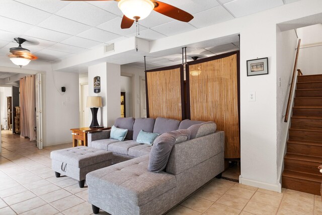 2120 73rd St, Galveston, TX 77551 - living area featuring light tile patterned floors, stairway, a paneled ceiling, a ceiling fan, and baseboards
