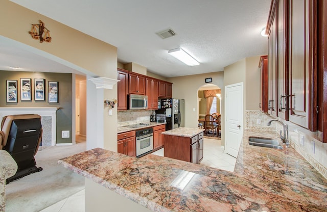 11939 Galentine Pt, Cypress, TX 77429 - kitchen with appliances with stainless steel finishes, a sink, arched walkways, a kitchen island, and light tile patterned floors
