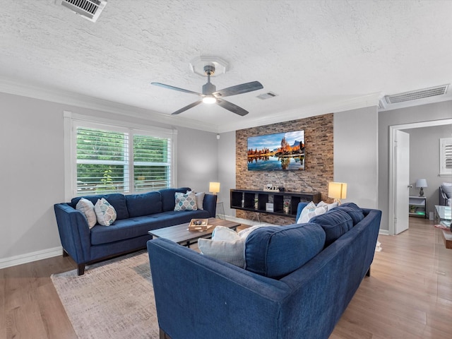 living room with light wood-type flooring, a textured ceiling, a ceiling fan, ornamental molding, and baseboards