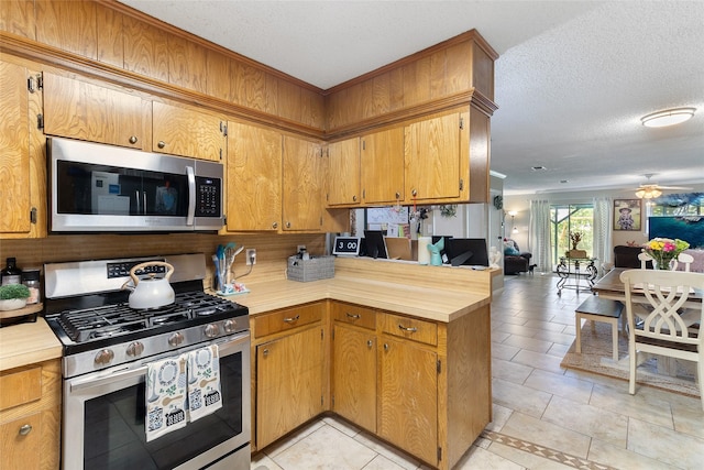1448 Camellia Dr, Sweeny, TX 77480 - kitchen with stainless steel appliances, open floor plan, a textured ceiling, ceiling fan, and a peninsula