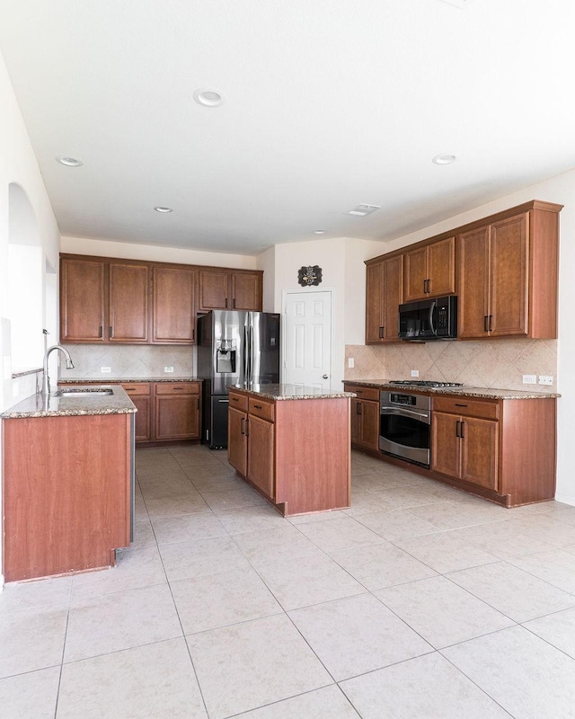kitchen featuring appliances with stainless steel finishes, a sink, backsplash, stone counters, and recessed lighting