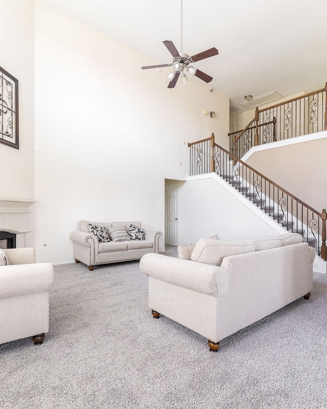 carpeted living room with a towering ceiling, ceiling fan, and stairway