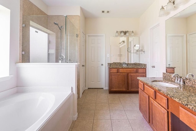 bathroom featuring a stall shower, tile patterned flooring, a garden tub, and two vanities