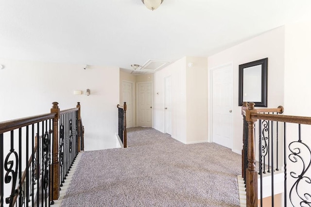 hall featuring an upstairs landing, attic access, light colored carpet, and baseboards