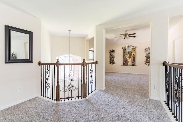 hall with carpet flooring, an upstairs landing, a chandelier, and baseboards