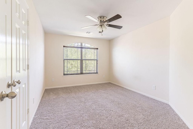 carpeted empty room with a ceiling fan and baseboards