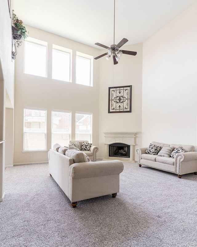 living room with carpet floors, a high ceiling, a ceiling fan, and a premium fireplace