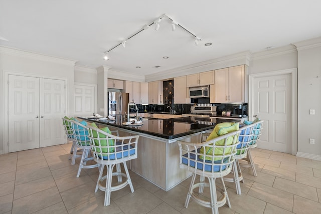 180 Hummel Ln, Coldspring, TX 77331 - kitchen with appliances with stainless steel finishes, dark countertops, light brown cabinets, a kitchen bar, and a spacious island