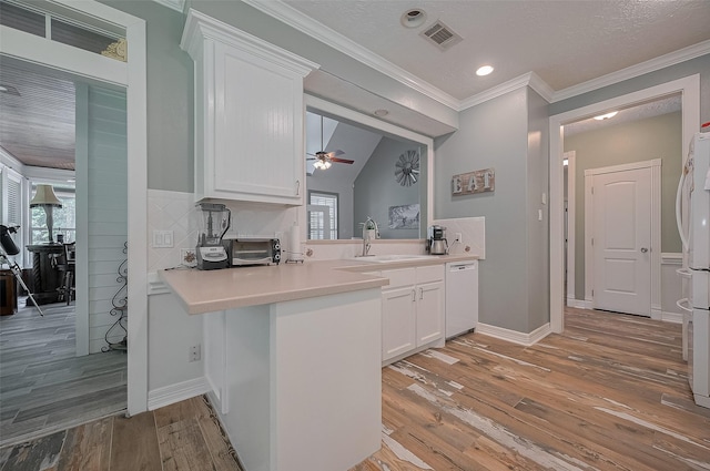 8946 Catamaran Way, Montgomery, TX 77316 - kitchen with a sink, white dishwasher, white cabinets, light wood finished floors, and crown molding