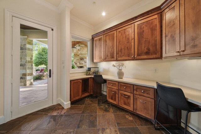 7527 Foster Island Dr, Richmond, TX 77406 - kitchen with dark stone finish flooring, light countertops, crown molding, brown cabinets, and baseboards