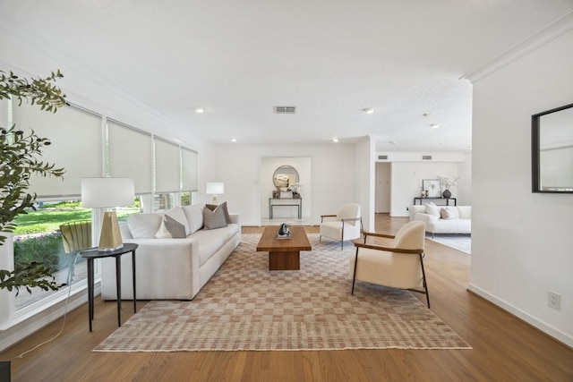 living area featuring wood finished floors, crown molding, and baseboards