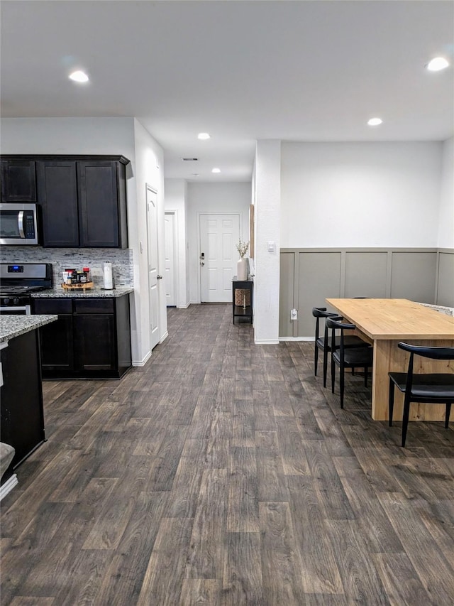 18475 Tenaha Mill Dr, New Caney, TX 77357 - kitchen featuring appliances with stainless steel finishes, dark wood-style floors, light stone counters, backsplash, and recessed lighting