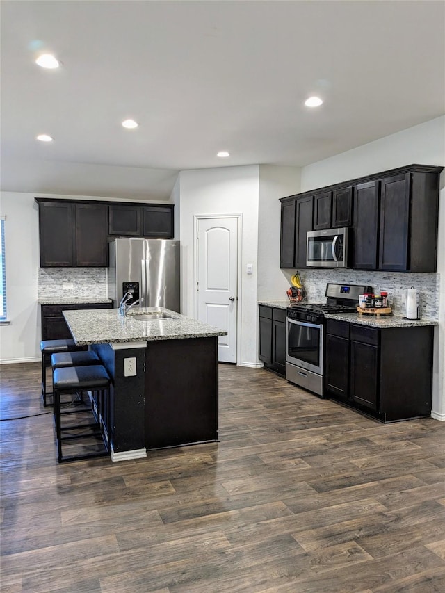 18475 Tenaha Mill Dr, New Caney, TX 77357 - kitchen featuring stainless steel appliances, tasteful backsplash, recessed lighting, light stone counters, and dark wood-style flooring