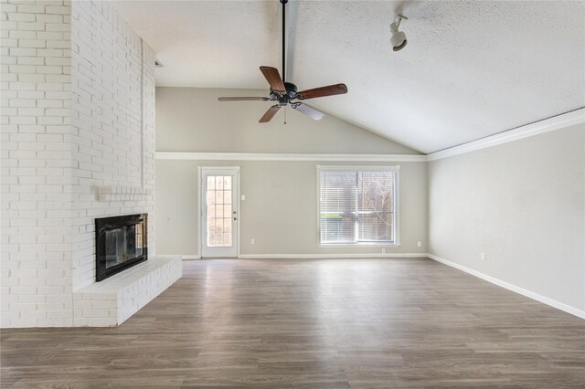 2036 Woodland Hills Dr, Missouri City, TX 77489 - unfurnished living room with vaulted ceiling, a ceiling fan, wood finished floors, a brick fireplace, and a textured ceiling