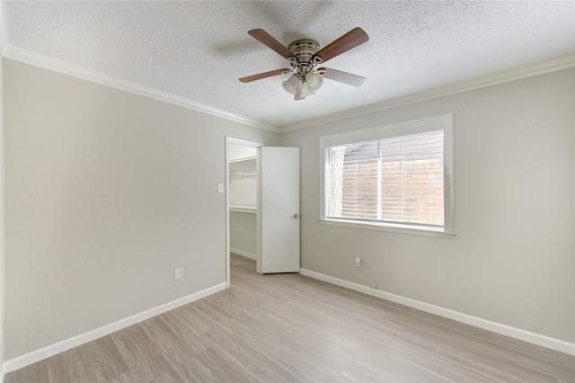 2036 Woodland Hills Dr, Missouri City, TX 77489 - unfurnished bedroom with a textured ceiling, light wood-style floors, ornamental molding, baseboards, and a spacious closet