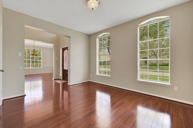 empty room with wood finished floors, baseboards, and a chandelier