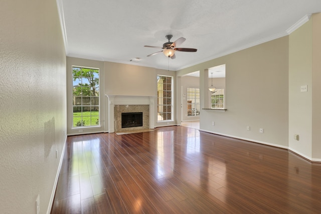 unfurnished living room with a ceiling fan, ornamental molding, wood finished floors, baseboards, and a fireplace