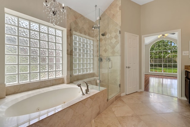 full bathroom with a tub with jets, a shower stall, a chandelier, tile patterned floors, and a high ceiling