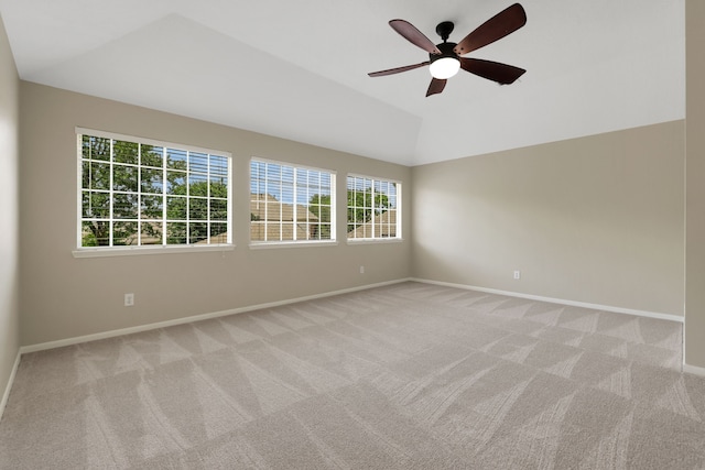 spare room featuring light colored carpet, a ceiling fan, baseboards, and vaulted ceiling