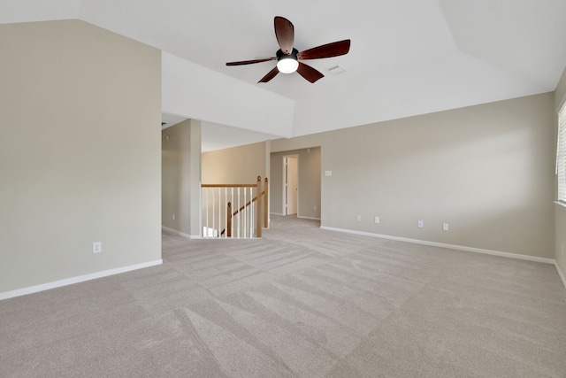 empty room featuring vaulted ceiling, ceiling fan, light colored carpet, and baseboards