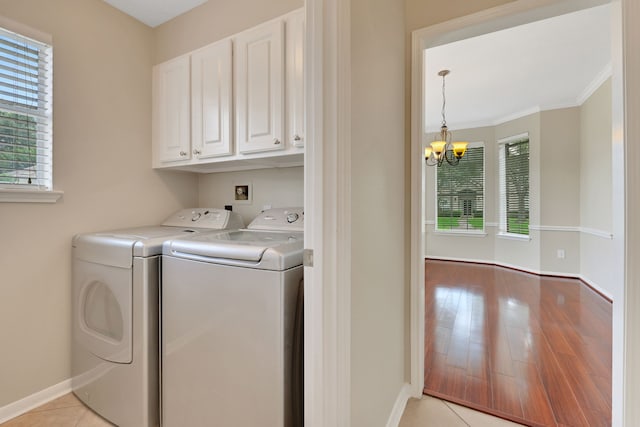 laundry room with cabinet space, washing machine and dryer, plenty of natural light, a chandelier, and crown molding