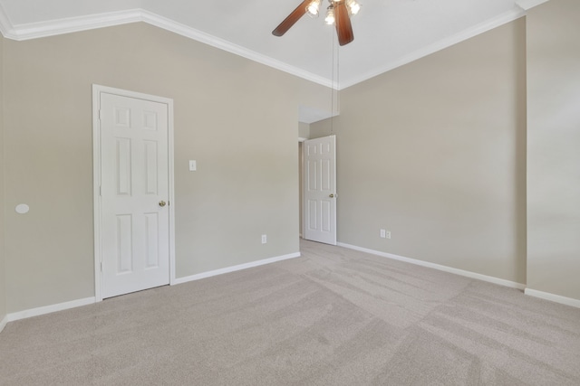 empty room with ceiling fan, carpet, vaulted ceiling, baseboards, and ornamental molding