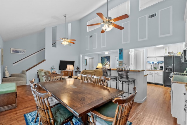268 Seminole Dr, League City, TX 77565 - dining space with ceiling fan, high vaulted ceiling, stairs, and light wood finished floors