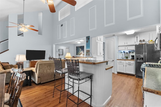 268 Seminole Dr, League City, TX 77565 - kitchen with ceiling fan, a kitchen bar, open floor plan, black fridge, and a towering ceiling
