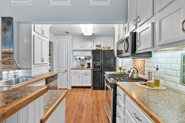 268 Seminole Dr, League City, TX 77565 - kitchen featuring stainless steel appliances, a sink, white cabinets, decorative backsplash, and light wood-style flooring
