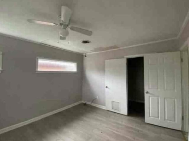 101 W St, Liberty, TX 77575 - unfurnished bedroom featuring baseboards, wood finished floors, and a ceiling fan