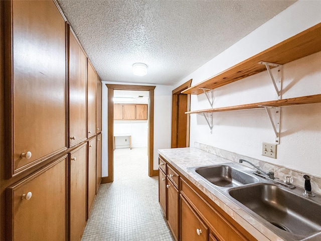 102 Besch Wilburn Ln, Glidden, TX 78943 - kitchen with open shelves, a sink, brown cabinets, a textured ceiling, and light countertops