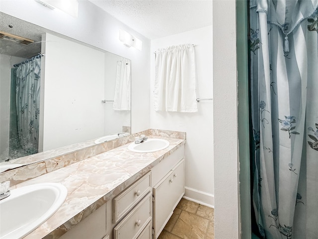 102 Besch Wilburn Ln, Glidden, TX 78943 - full bath featuring baseboards, double vanity, stone tile flooring, a textured ceiling, and a shower with shower curtain