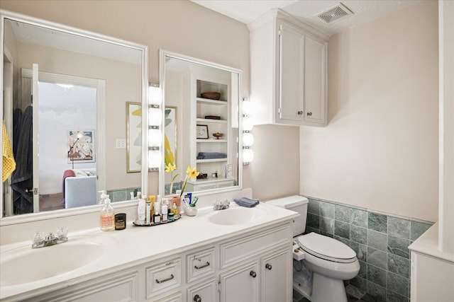 1755 Kipling St, Houston, TX 77098 - bathroom featuring toilet, wainscoting, double vanity, and tile walls