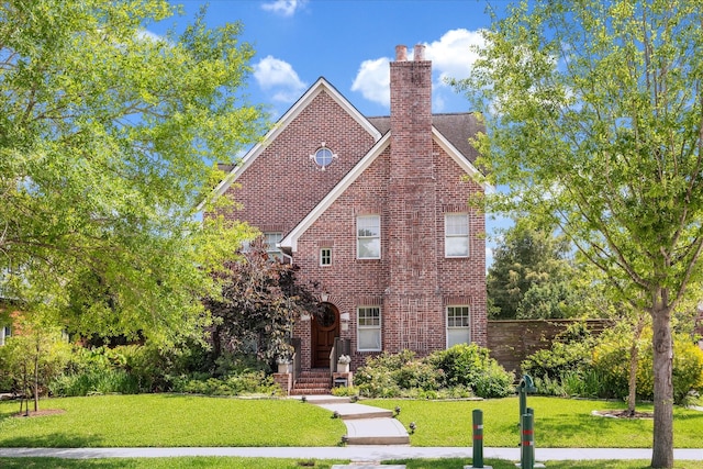 1755 Kipling St, Houston, TX 77098 - tudor house featuring a front lawn, a chimney, and brick siding