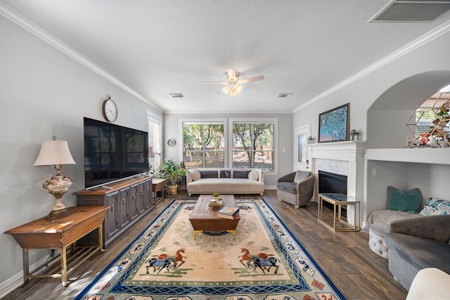 living area featuring a ceiling fan, wood finished floors, plenty of natural light, ornamental molding, and a fireplace