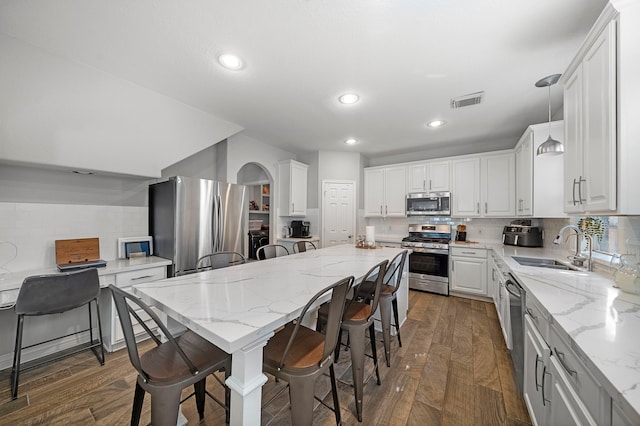 kitchen with appliances with stainless steel finishes, a sink, backsplash, a kitchen bar, and recessed lighting