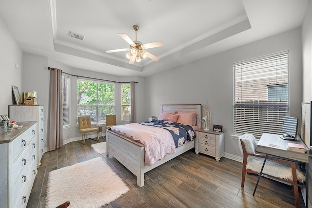 bedroom with a raised ceiling, ornamental molding, dark wood-style floors, baseboards, and a ceiling fan