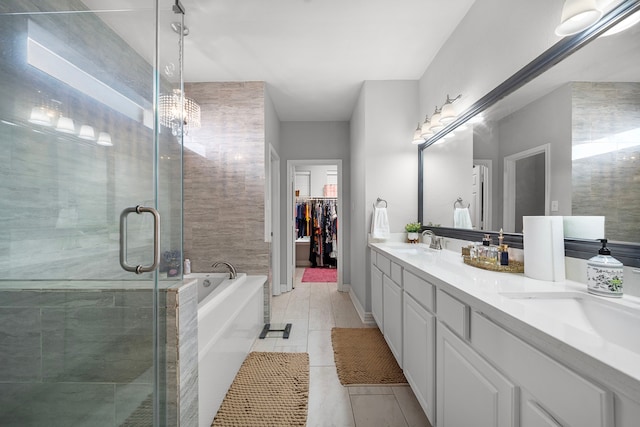 bathroom featuring a garden tub, double vanity, a stall shower, a spacious closet, and a chandelier