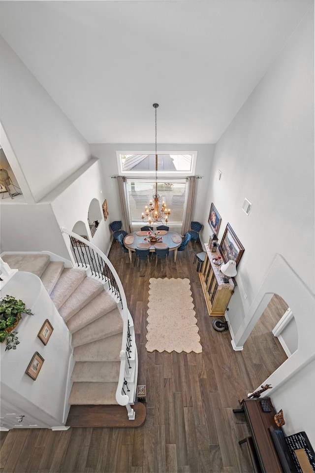 dining space with wood finished floors, a chandelier, and stairs