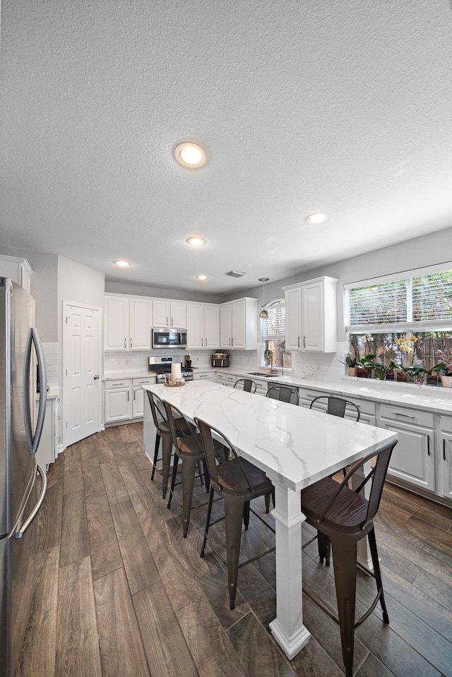 dining space featuring dark wood finished floors, recessed lighting, and a textured ceiling