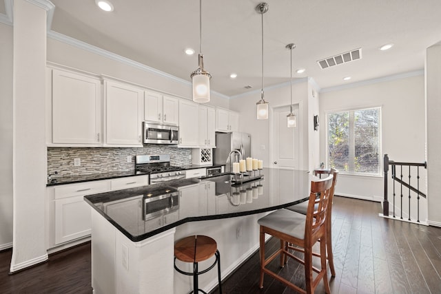 8907 Wind Springs Dr, Houston, TX 77080 - kitchen featuring stainless steel appliances, an island with sink, backsplash, a kitchen breakfast bar, and ornamental molding