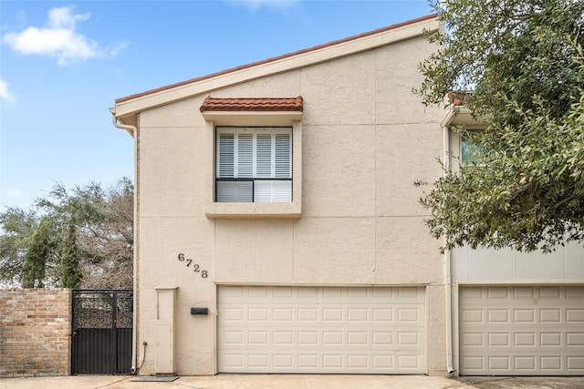 6728 Buffalo Speedway, West University Place, TX 77005 - view of front of property with stucco siding, an attached garage, a gate, and fence