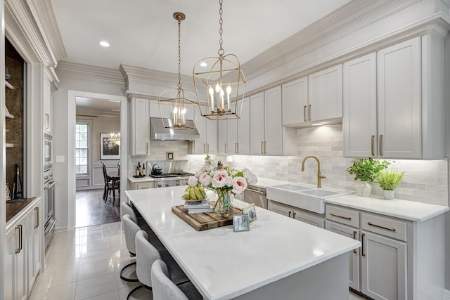 kitchen with a sink, a chandelier, a breakfast bar area, pendant lighting, and backsplash