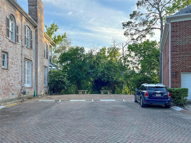 uncovered parking lot featuring view of wooded area