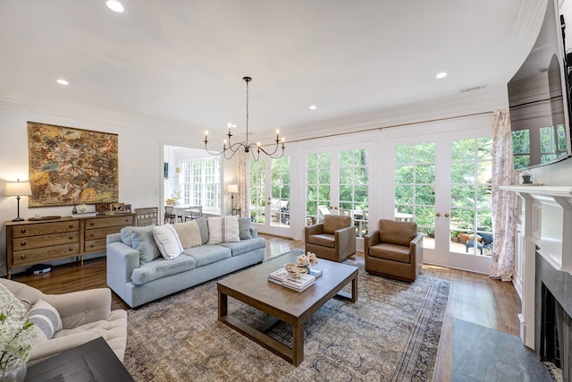 living room featuring a fireplace with flush hearth, crown molding, a chandelier, wood finished floors, and recessed lighting