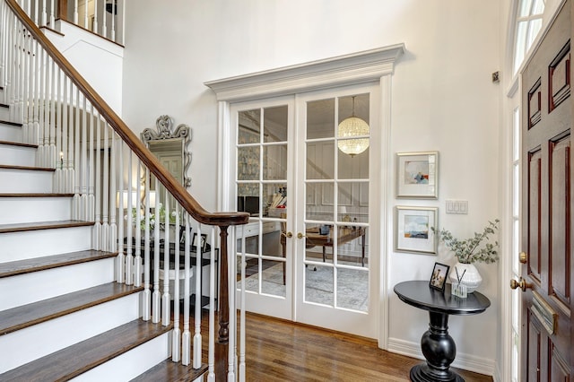 foyer featuring french doors, stairs, wood finished floors, baseboards, and a towering ceiling